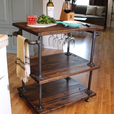 Three-tier industrial bar cart with pipes and hanging wine glasses and casters