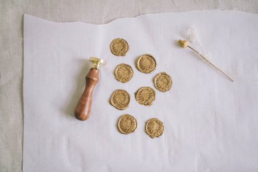 Eight gold wax seals cooling on parchment paper