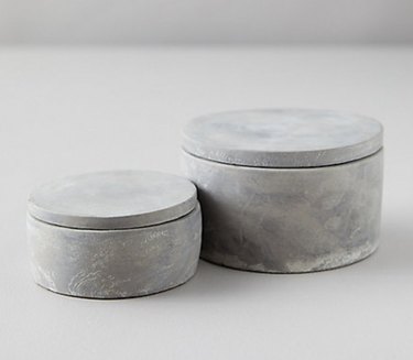 Two cement jars with lids in two sizes.