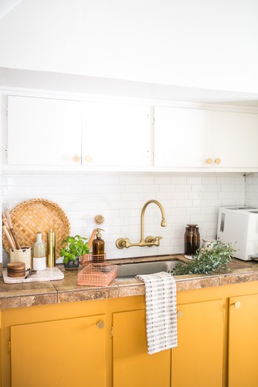 kitchen space with white and mustard cabinets and gold sink faucet