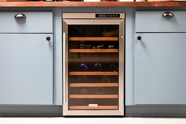 close up of wine fridge, blue kitchen cabinetry and modern kitchen knobs