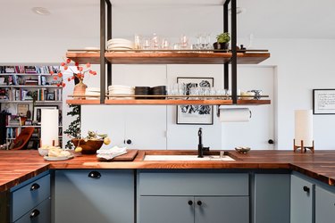 open kitchen with butcher block counter, undermount sink, hanging shelves