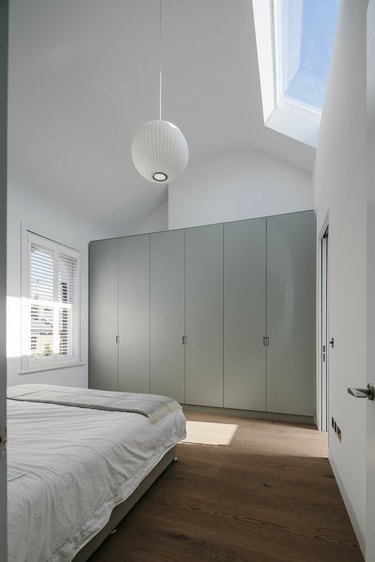 light, bright master bedroom with built-in closet and George Nelson pendant light