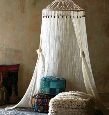 Gauze and macrame canopy hung from ceiling with floor pillows.