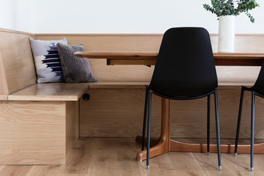 wooden banquette surrounding table with black chairs