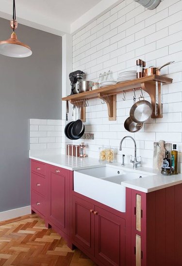 Kitchen with maroon lower cabinets, white subway tile and gray walls