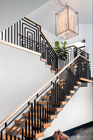 Art Deco staircase with black geometric railings and large pendant light
