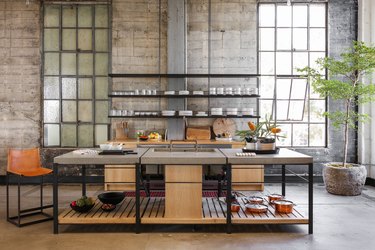 concrete industrial kitchen island with wooden shelf and metal legs in loft apartment