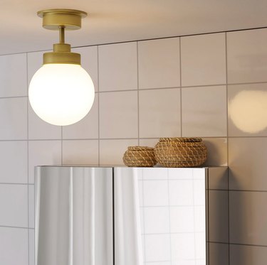 IKEA bathroom lighting idea with brass ceiling light and white tile wall