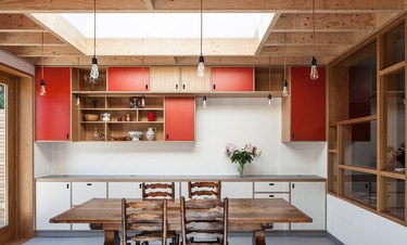 red kitchen cabinet color with warm wood and rustic dining table