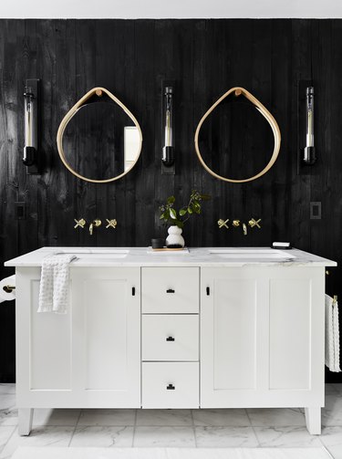 Bathroom with black panel walls, white vanity.