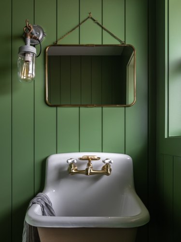 rustic bathroom lighting idea with wall sconce near mirror on green shiplap wall