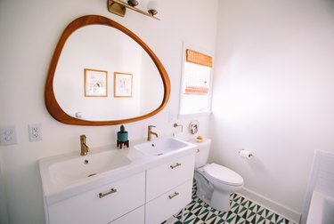 modern bathroom with amorphous mirror over double vanity