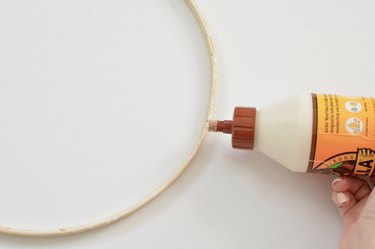 Wood glue being applied to wooden hoop.