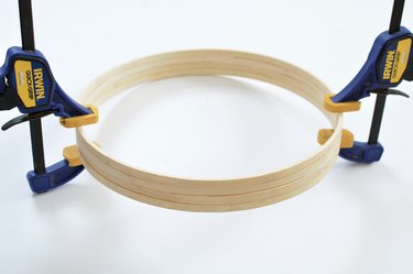 Blue and yellow hand clamps holiding together wooden hoops.