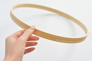 Hand holding two wooden hoops glued together