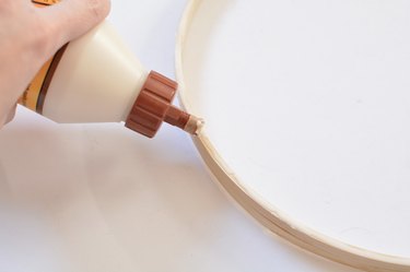 Bottle of wood glue being applied to wooden hoops.