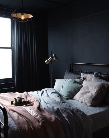 dark minimalist bedroom with seafoam bedding and pink blanket