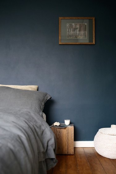dark minimalist bedroom with wood box nightstand and dark blue wall