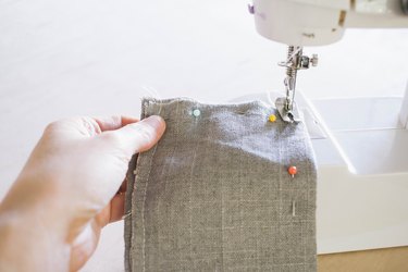 Sewing gray linen fabric pieces together with sewing machine