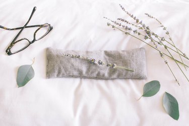 Gray linen eye pillow on top of white pillow with dried lavender