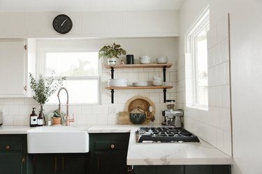 apron-front white cast iron sink inset in black cabinetry beneath exposed shelving
