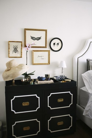 Hollywood regency bedroom with gallery wall and black Dorothy Draper nightstand