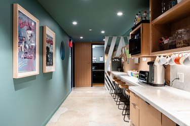 galley-style kitchen with green walls, overhead lighting and stools