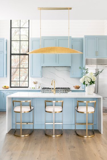 pastel blue kitchen island with marble waterfall countertop