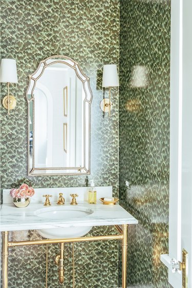 hollywood regency bathroom with brass details and green wallpaper