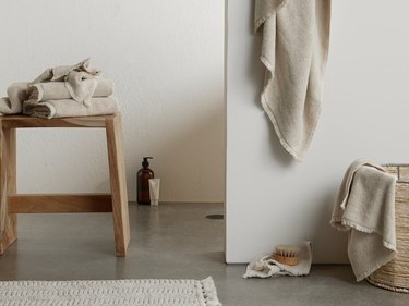 bathroom space with stool and basket and neutral towels