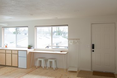 simple minimalist living space with cabinet, large windows, wood floor