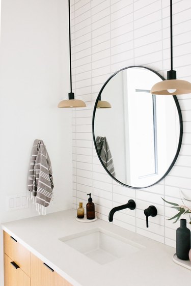 bathroom mirror idea with circle mirror with black frame and white metro tiles in bathroom