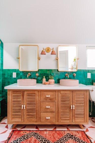 green tiled bohemian bathroom lighting idea with wooden vanity and pink wall lights