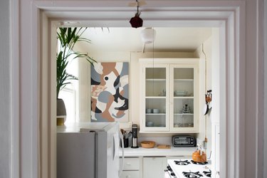 small kitchen with glass-faced kitchen countertops, a stove and abstract art on the wall