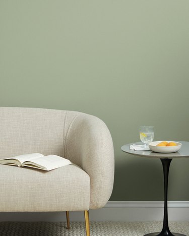 beige couch with table nearby and green wall