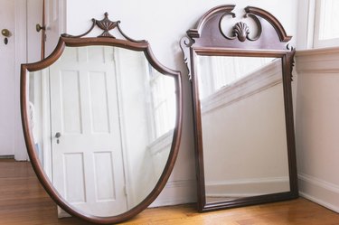 Two dark wood thrift store mirrors leaned against wall