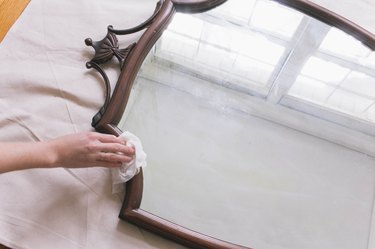 Cleaning wood frame of thrift store mirror with cloth