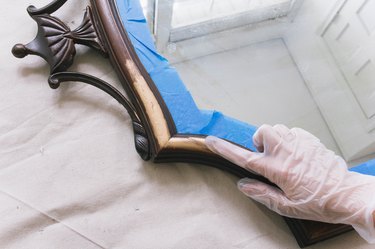 Rubbing gilding wax onto wooden mirror frame with latex glove