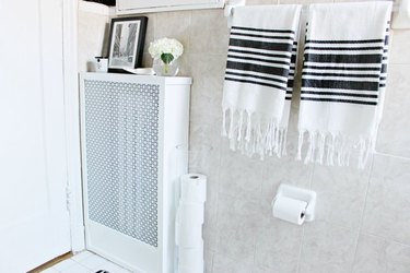 White radiator cover in bathroom with black and white towels