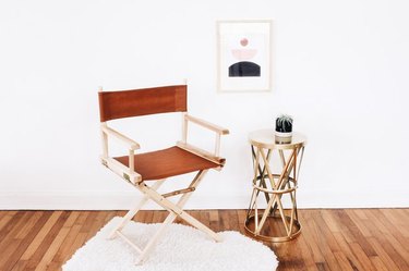 Leather director's chair next to brass side table on white rug