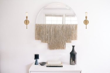 Fringe mirror between two sconces