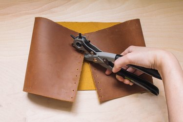 Punching holes on dots marked on leather with leather punch tool