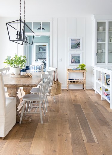 coastal dining room with uphsoltered head chairs and windsor chairs with rattan bar cart