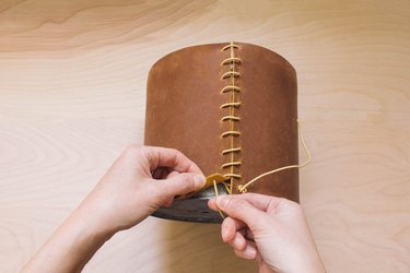 Threading leather cord through bottom hole of leather wrapped planter