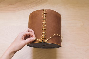 Tying double knot on leather cord at bottom hole of leather wrapped planter