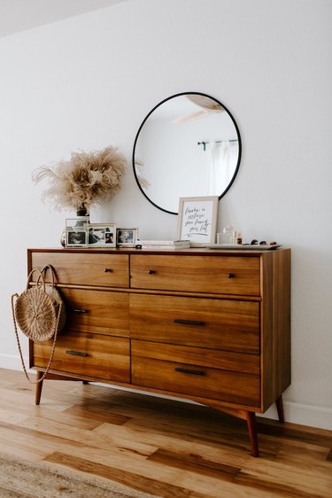 bedroom with wood dresser and round mirror