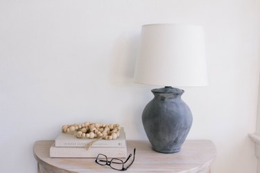 Thrift store lamp painted with chalkboard paint on top of table with books and beads