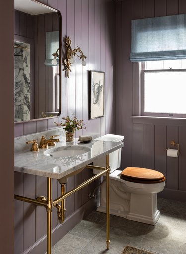 ornate gold trending bathroom lighting in bathroom with purple shiplap walls and marble sink