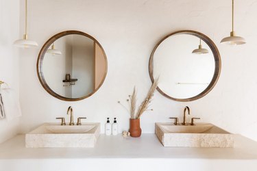 trending bathroom lighting in white bathroom with double vanity and circle mirrors